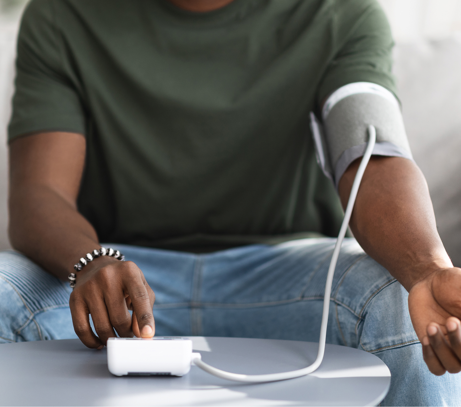 A man taking his blood pressure at home with an arm cuff and monitor